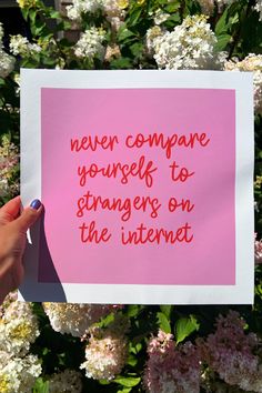 someone holding up a pink piece of paper that says never compare yourself to strangers on the internet