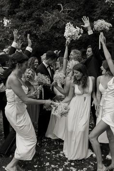 a group of people standing around each other holding bouquets in the air with their hands up