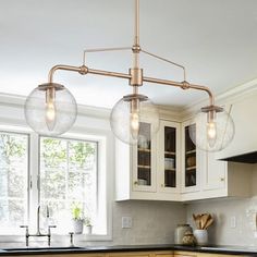 a kitchen with white cabinets and black counter tops in front of a window that has glass globes hanging from the ceiling