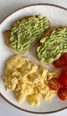 two pieces of toast with avocado and tomatoes on them are sitting on a plate