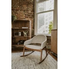 a rocking chair sitting in front of a window next to a book shelf and bookshelf