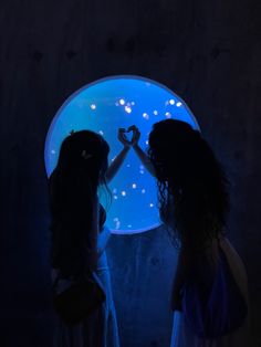 two girls standing in front of a blue light holding hands