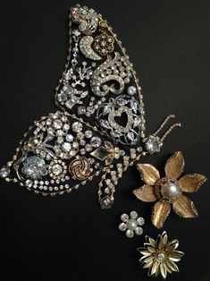 two brooches are sitting next to each other on a black surface with flowers