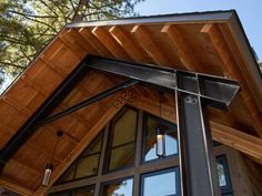 the top of a house with wood and metal trim on it's roof, which is attached to a pole