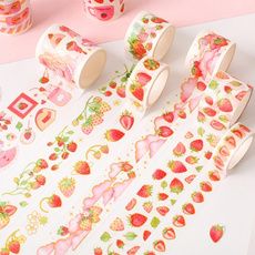 washi tape with strawberrys on them sitting on a pink surface next to other washi tapes