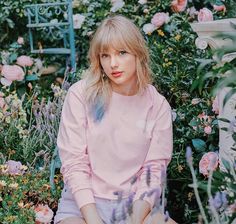 a woman sitting on the ground in front of some flowers and plants with her eyes closed