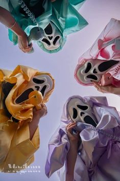 four people holding masks in the air with one person wearing them as if they are looking up