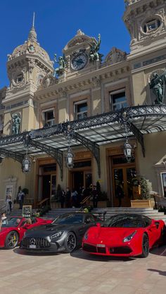 three red sports cars parked in front of a building with statues on the top of it