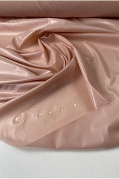 an image of a pink satin material with water drops on the fabric and it is very soft