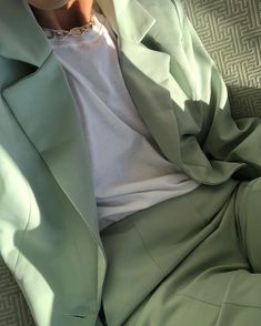 a man laying on top of a couch wearing a green suit and white t - shirt