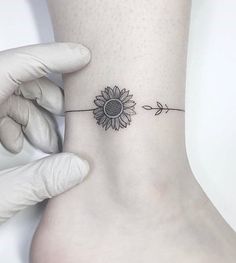 a person with a sunflower tattoo on their ankle is holding up the side of her foot