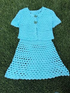 a crocheted blue dress laying on the grass