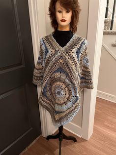 a mannequin wearing a crocheted sweater on top of a wooden table