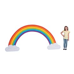 a girl standing in front of a rainbow cutout with clouds on the bottom and top