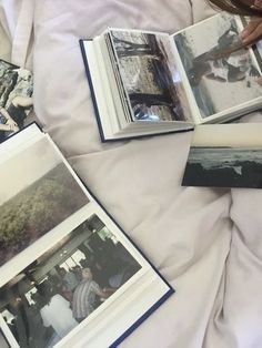 an open book laying on top of a bed next to two pictures and a person