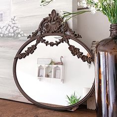 a mirror sitting on top of a table next to a vase with flowers in it