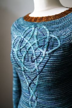 a knitted sweater with an intricate design on the chest and shoulders, along with a white mannequin's head