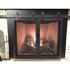 an open fireplace with logs burning in it's side and two doors on each side