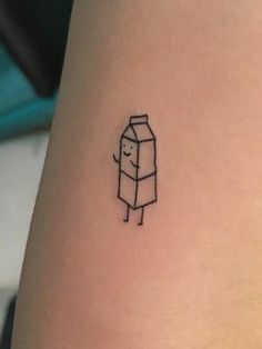 a small tattoo of a carton of milk on the thigh, with an outline of a cartoon character