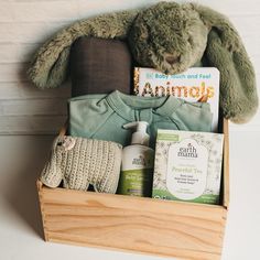 a teddy bear sitting in a wooden box filled with baby items