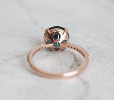 a rose gold ring with blue topaz and black diamond in the center on a white surface