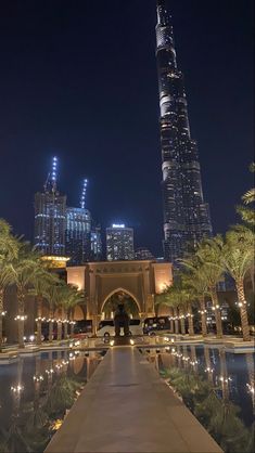 the burj building is lit up at night with palm trees and lights around it