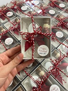 someone is holding a small box with some cookies in it and wrapped around red ribbon