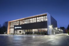 an empty parking lot in front of a building with lights on the side of it