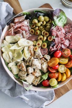 a bowl filled with different types of food on top of a wooden cutting board next to a knife and fork