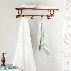 two towels hanging on a towel rack next to a white sink and green plants in a bathroom