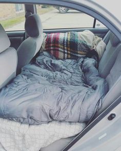 the back seat of a car with an unmade bed in it