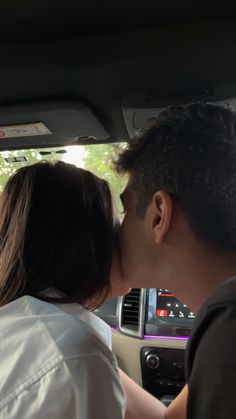 a man and woman kissing in the back seat of a car