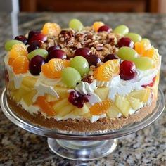 a cake with fruit and nuts on top is sitting on a glass platter in the kitchen