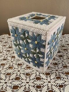 a small blue and white box sitting on top of a doily covered tablecloth