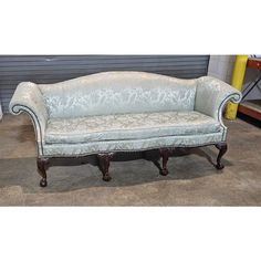 an old fashioned couch sitting on top of a hard wood floor next to a garage door