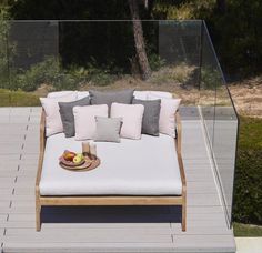 a white couch sitting on top of a wooden floor next to a swimming pool and trees