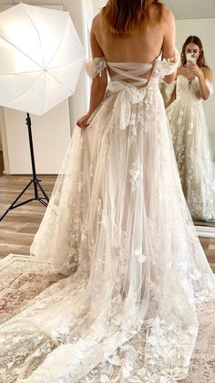 a woman in a wedding dress is taking a selfie with her cell phone while looking at herself in the mirror