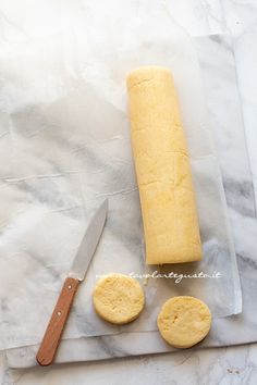 a loaf of bread, two cookies and a knife on a cutting board with parchment paper