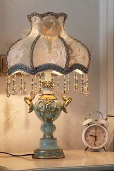 a blue lamp sitting on top of a table next to an alarm clock and wall