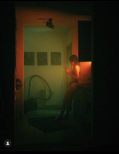 a woman is sitting in the dark holding an object