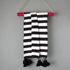 a black and white striped towel hanging on a rope with tassels attached to it