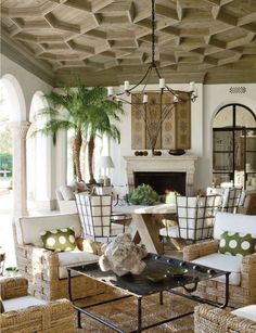 a living room with wicker furniture and palm trees in the background, along with an open fire place