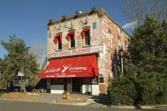 an old brick building with red awnings on the front and side of it