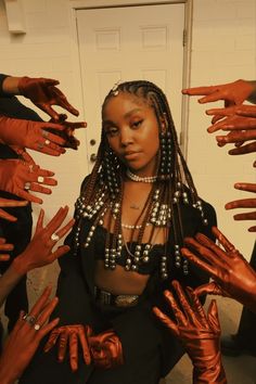 a woman sitting in front of a door covered in orange painted hands and bracelets