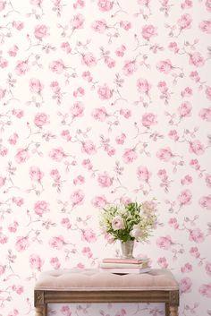 a vase with flowers sitting on top of a wooden bench next to a wallpaper