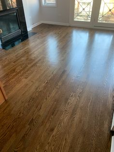 an empty living room with hard wood flooring and glass doors leading to a fireplace