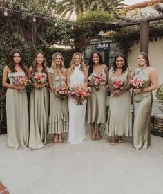 a group of women standing next to each other holding bouquets in front of a building