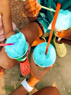 two people sitting on the ground holding cups with ice cream and strawberries in them