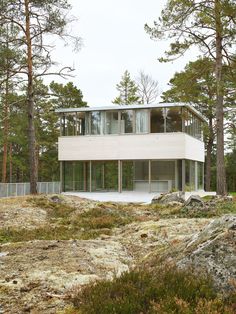 a white house sitting on top of a lush green hillside next to tall pine trees