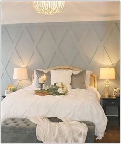 a bed with white sheets and pillows in a bedroom next to two lamps on either side of the bed